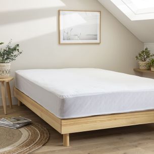 Protège matelas en coton bio imperméable posé sur un lit, ambiance douce et naturelle