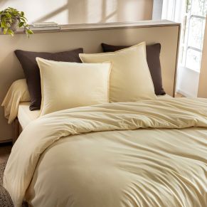 Lit douillet avec housse de couette coton lavé jaune dans une chambre lumineuse au style bohème