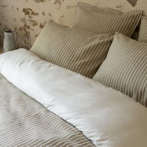 Housse de couette Dune coloris sable dans une chambre authentique aux murs en pierre