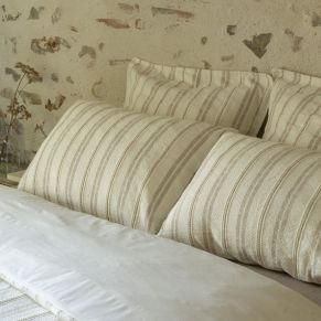 Taie d'oreiller Olympe sur un lit king size dans une chambre authentique avec mur en briques